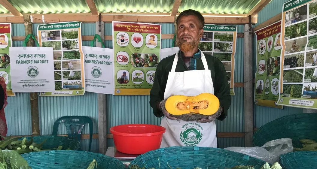 A man standing at his market stand selling vegetables