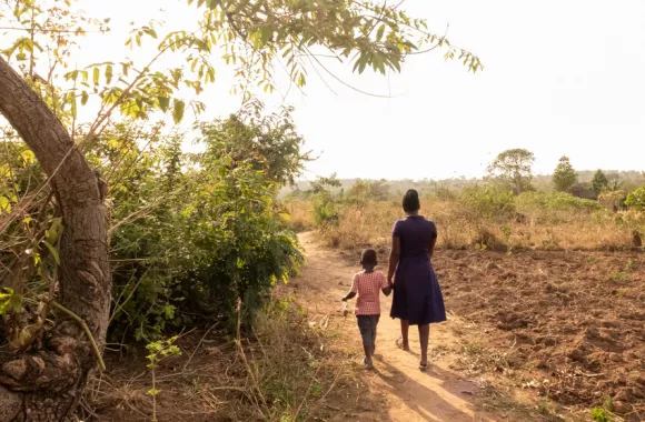 Mary Ilero, 30, walks through a field with her son Ephraim Ekadu at the family’s farm outside of Soroti City, Uganda.